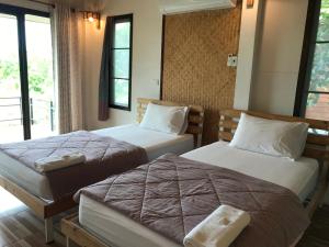 乌泰他尼府บ้านกลางเกาะ รีสอร์ท的酒店客房设有两张床和窗户。