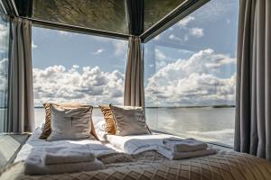 梅尔诺Domki na wodzie - Grand HT Houseboats - with sauna, jacuzzi and massage chair的一张位于带大窗户的房间内的床铺