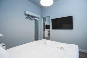 利耶帕亚Roze Park Rooms的卧室配有白色的床和平面电视。