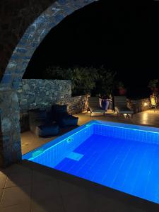 伊罗达Villa Helios的一座带石墙的夜间游泳池