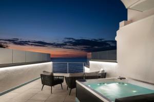 伊斯基亚伊斯基亚蓝光度假酒店的阳台设有热水浴池和桌椅。