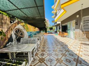 阿拉尼亚Alanya Queen Apart Otel的铺有瓷砖地板,设有带桌椅的庭院。