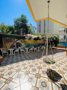 阿拉尼亚Alanya Queen Apart Otel的庭院铺有瓷砖地板,配有椅子和遮阳伞。