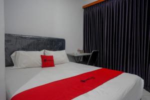 RempawahRedDoorz At Jalan Raya Baturaden的一间酒店客房,床上铺有红色毯子