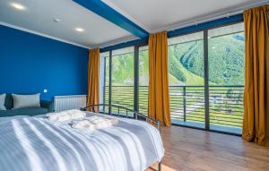卡兹贝吉Hotel Darchi Kazbegi的蓝色卧室设有床和大窗户