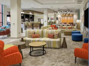 维塞利亚Hilton Garden Inn Visalia, Ca的一间大厅,在商店里摆放着长沙发和桌子