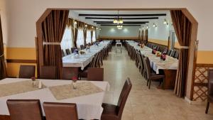 CoşnaPensiune Restaurant Cosna的一间长餐厅,配有白色的桌子和椅子