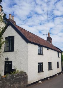 LangfordBay Tree Cottage的白色的房子,设有黑窗和屋顶