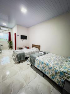 Serra de São BentoPousada Serrana的客房设有两张床和一台平面电视。