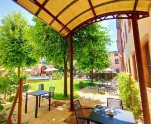蒙托邦Abbaye des Capucins Spa & Resort的户外庭院配有桌椅和树木。