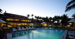 纳塔尔Hotel Marsol Beach Resort的一座带椅子和遮阳伞的游泳池位于一座建筑旁边