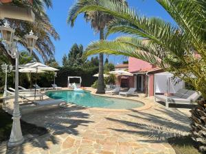 圣马克西姆Fantastic pool villa 900m to the beach; with extravagant big garden的庭院内一个带椅子和棕榈树的游泳池