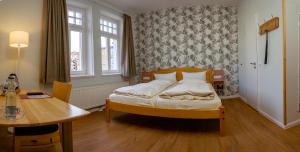 石勒苏益格阿尔特克雷斯班霍夫酒店的一间小卧室,配有一张床和一张桌子
