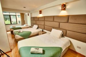 库斯科因迪坦普旅馆的酒店客房,配有两张带绿床单的床