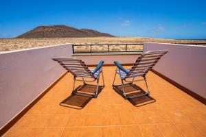 塞博河畔卡莱塔Eslanzarote El Ancla House, wifi, Sea views的两把椅子坐在房子的屋顶上