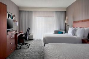 惠帕尼Sonesta Select Whippany Hanover的酒店客房设有两张床、一张桌子和一台电视。