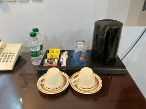 达曼Arrawiya Alzahabia Hotel的一张桌子,上面放着两个杯子和盘子,还有咖啡壶