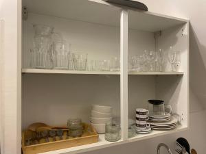 伦敦Cosy flat in London的装满玻璃杯和盘子的橱柜