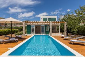 特罗吉尔Villa Trogir save 15 percent on Split-villas com的房屋旁的游泳池配有椅子和遮阳伞