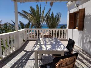 奇波斯阿费提Palmhouses的阳台上配有白色的桌椅,享有海景