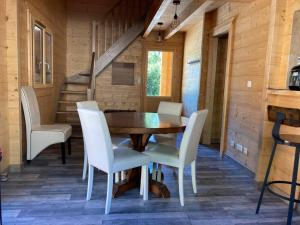 AlièzeForest Jura Lodge - Chalet des sapins的一间带木桌和白色椅子的用餐室