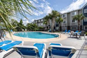 卡罗来纳比奇The Windstar Hotel - Carolina Beach的一座带蓝色椅子的游泳池和一座建筑