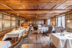 弗劳恩费尔德克罗伊茨黄金酒店的餐厅设有白色的桌椅和木制天花板。