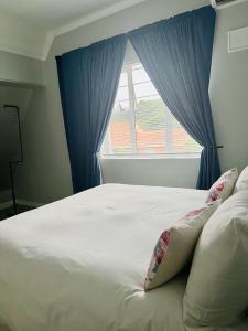 德班Bella Lux Villa的白色的床,配有蓝色窗帘和窗户