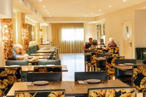 巴塞罗那卡利多尼安酒店的一间设有桌子的餐厅,有坐在桌子上的人