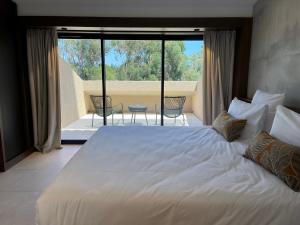 维琪奥港Hôtel Spa & Restaurant - Son de Mar的一间带一张白色大床的卧室和一个阳台