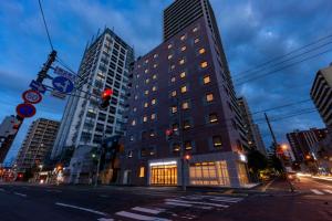 札幌plat hostel keikyu sapporo ichiba的夜幕降临的城市街道上一座高楼