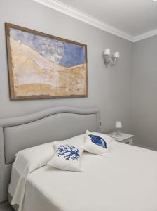 利帕里Lipari Suite B&B的卧室配有白色的床和墙上的绘画作品