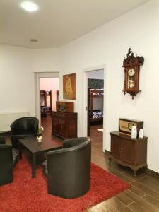 布拉索夫Vintage Downtown Hostel的客厅配有椅子、桌子和时钟
