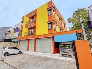 万隆OYO 91364 Pondok Alfa的一座黄色和橙色的建筑,前面有停车位