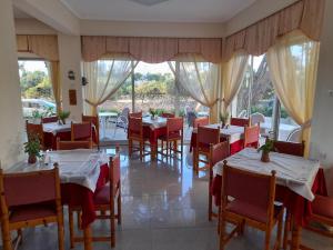 科斯镇法厄同酒店的餐厅设有白色桌子和红色椅子,窗户