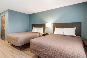 格林斯伯勒WoodSpring Suites Greensboro - High Point North的蓝色墙壁客房的两张床