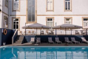 布拉加Hotel Villa Garden Braga的一座带椅子和遮阳伞的游泳池位于一座建筑旁边