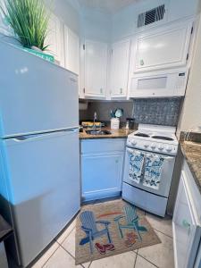 加尔维斯敦Sun Splashed Condo! Steps to Beach and 2 Pools Galveston Island的厨房配有白色冰箱和炉灶。