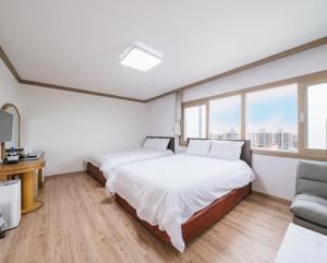 济州市Top Island Hotel的一间卧室设有两张床、一张沙发和窗户。