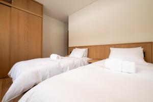 俱知安町Shion的配有白色床单的客房内的两张床