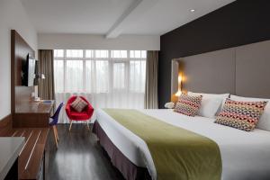 西安康铂酒店（西安钟楼回民街店）的酒店客房设有一张大床和一张红色椅子。
