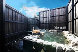 由布市Yufuin Yukari-an Megumi no Sato的后院的热水浴池,设有木栅栏