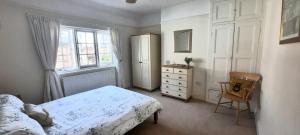曼海德Dumble Cottage的一间卧室配有一张床、一个梳妆台和一扇窗户。