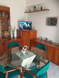 VilajuigaCASA LA SABONERA的一间设有玻璃桌和绿色椅子的用餐室