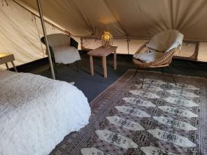 MuurameHideaway Glamping的一间卧室,在帐篷里配有一张床和椅子