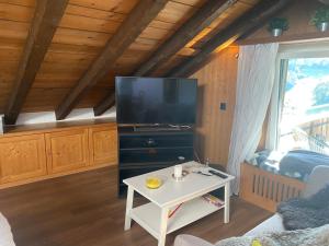 莱克斯Dachwohnung in der Mitte von Laax-Dorf的客厅配有电视和桌子