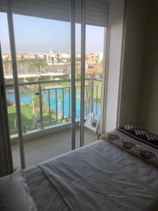 西迪拉哈尔Bel appartement pied sur mer vue imprenable sur piscine et jardins的一间卧室设有一张床和一个大窗户