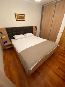 布德瓦子午线酒店的卧室配有一张白色大床,铺有木地板