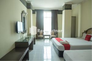 日惹Akur Hotel Malioboro Mitra RedDoorz的酒店客房设有两张床和电视。