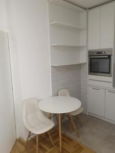 波德戈里察Jednosoban stan Zoja的白色的厨房配有桌子和两把椅子